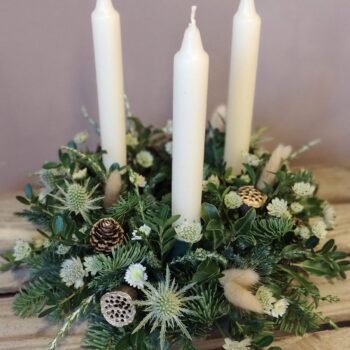 A round Christmas table arrangement in white and green.